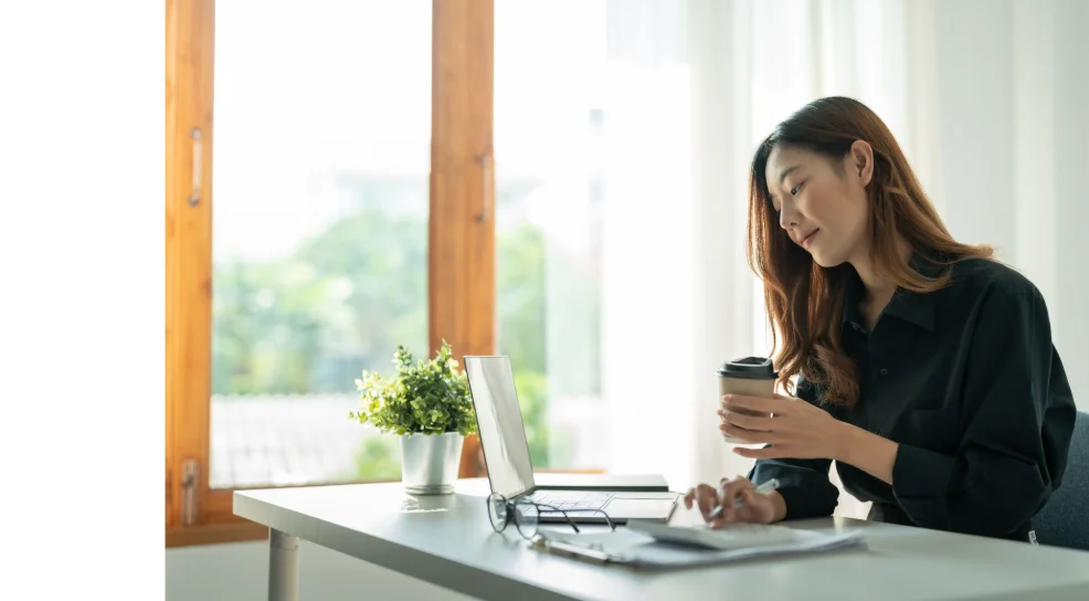 明るい窓辺でノートPCに向かう女性